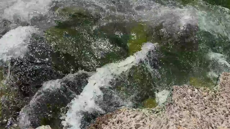 Un primo piano dall'alto dell'acqua del fiume che scorre contro le rocce.