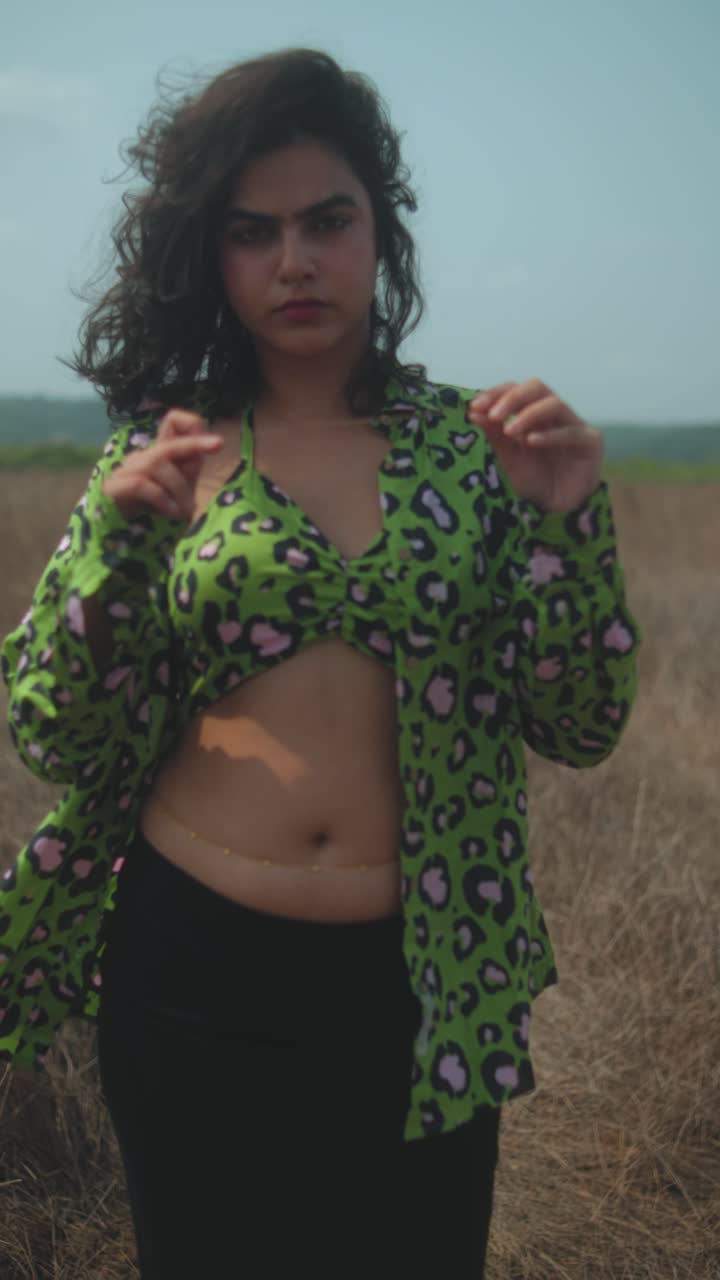 Young woman in stylish green leopard print shirt and black skirt in field