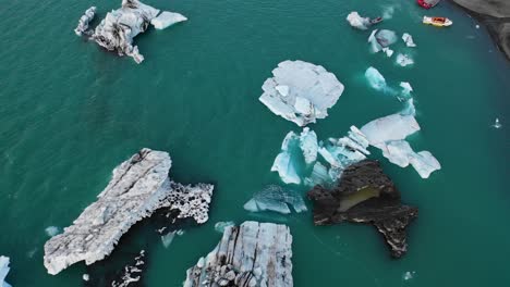 mirando hacia abajo drone sobrevuelo de icebergs en jokulsarlon con barcos saliendo de la laguna