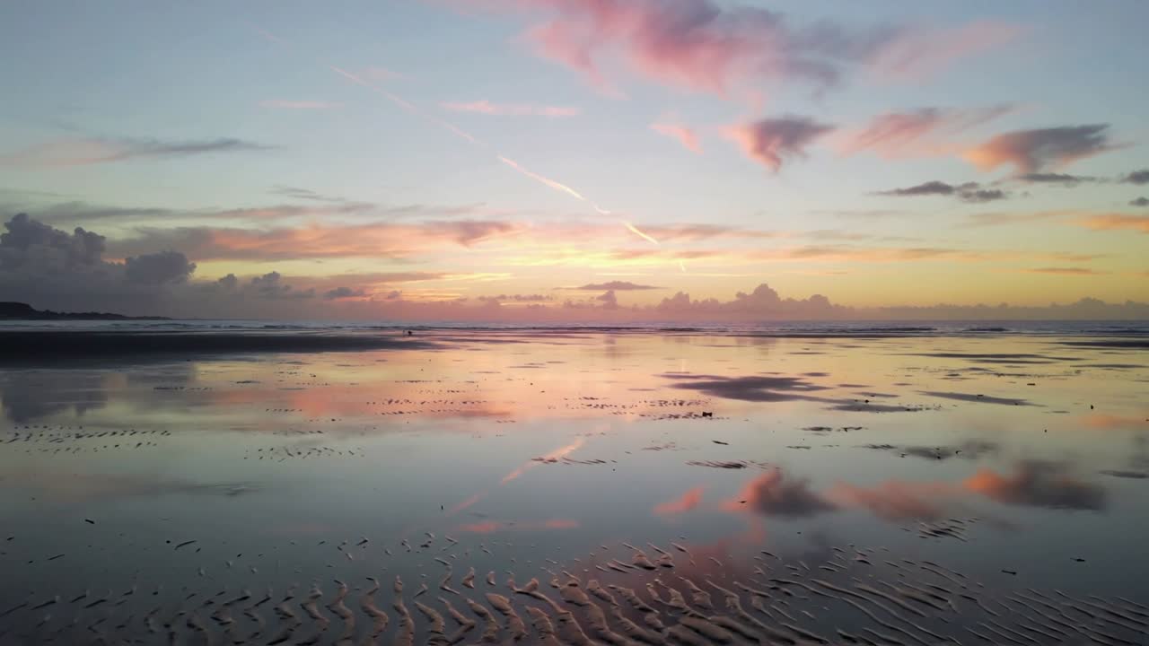 Reflecting tidal flat shifting ripples and gliding cloud mirrors as tide falling near headland