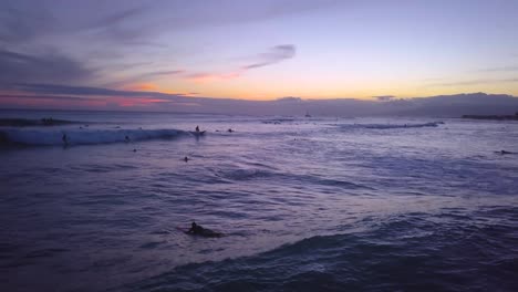 Surfer-Genießen-Den-Sonnenuntergang-In-Waikiki,-Wenn-Sie-Ihre-Letzten-Wellen-In-Der-Dämmerung-Auf-Der-Hawaiianischen-Insel-Oahu-Fangen