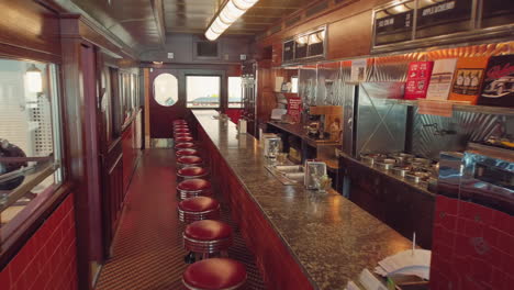 view into an empty nostalgic old fifties diner with lots of signs and a bar and stools