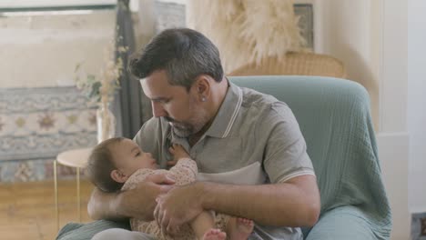 un joven guapo acunando a una niña linda en sus brazos.