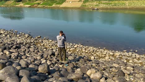 Person-taking-pictures-of-traditional-Bangladesh-boat-in-river-water,-back-view