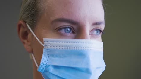 portrait of caucasian female doctor wearing face mask looking to camera
