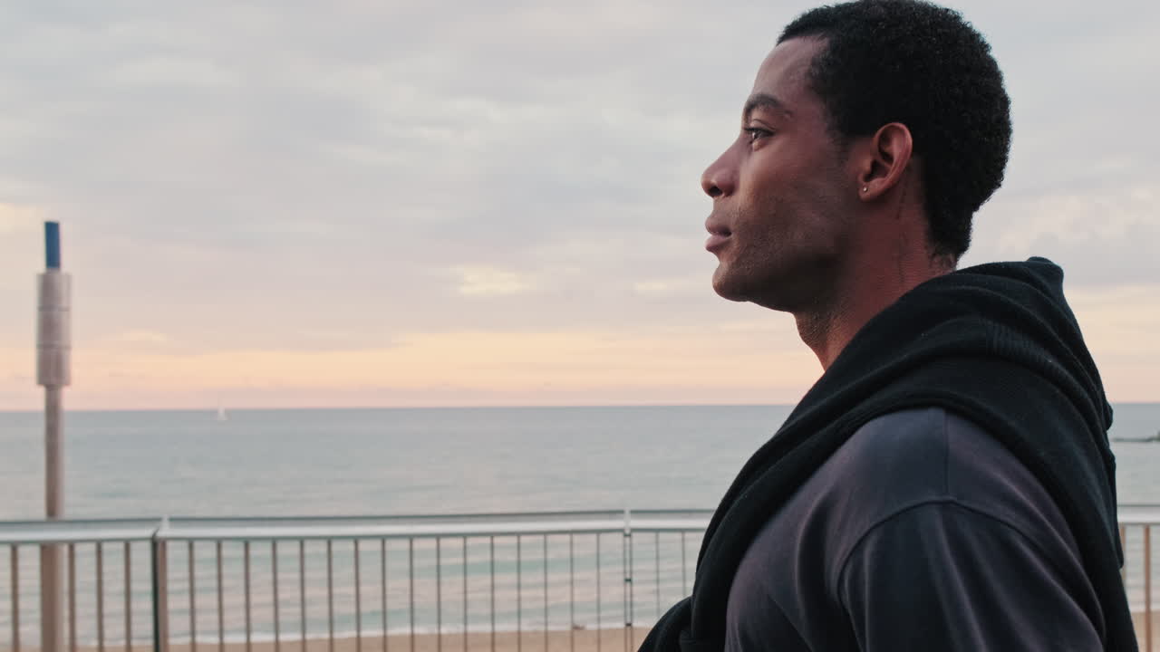 Young Man Looking Out at the Serene Ocean at Dusk