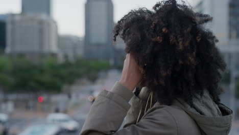 portrait-young-african-american-woman-puts-on-earphones-listening-to-music-in-city-enjoying-relaxed-urban-lifestyle-slow-motion-side-view