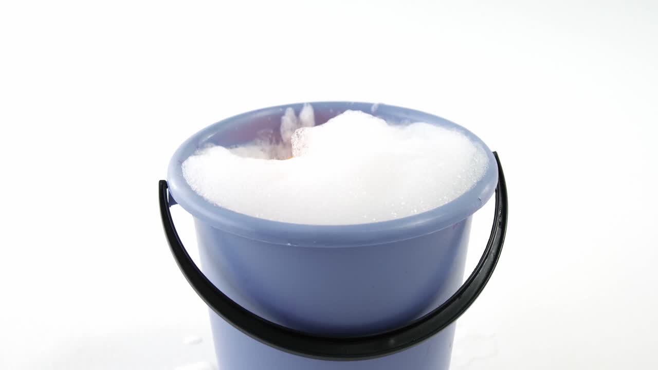 esponja de limpieza cayendo en un cubo de espuma de jabón