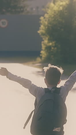 schoolboy throws away white paper sheets running to grey school gate with happiness slow motion backside view