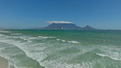 kitesurfistas montando en blouberg con la montaña de la mesa en el fondo