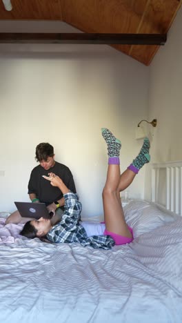 pareja relajándose y usando dispositivos en el dormitorio