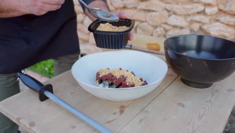 chef prepara comida mediterránea con atún crudo y almendras trituradas