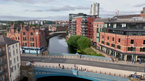 Drone camera smoothly pans across a Victorian-era bridge, red brick buildings, and riverside cityscape under daylight, highlighting urban architecture and river environment