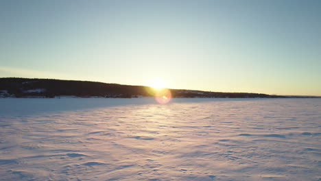 Flying-drone-above-a-frozen-lake-in-canada-at-golden-hour