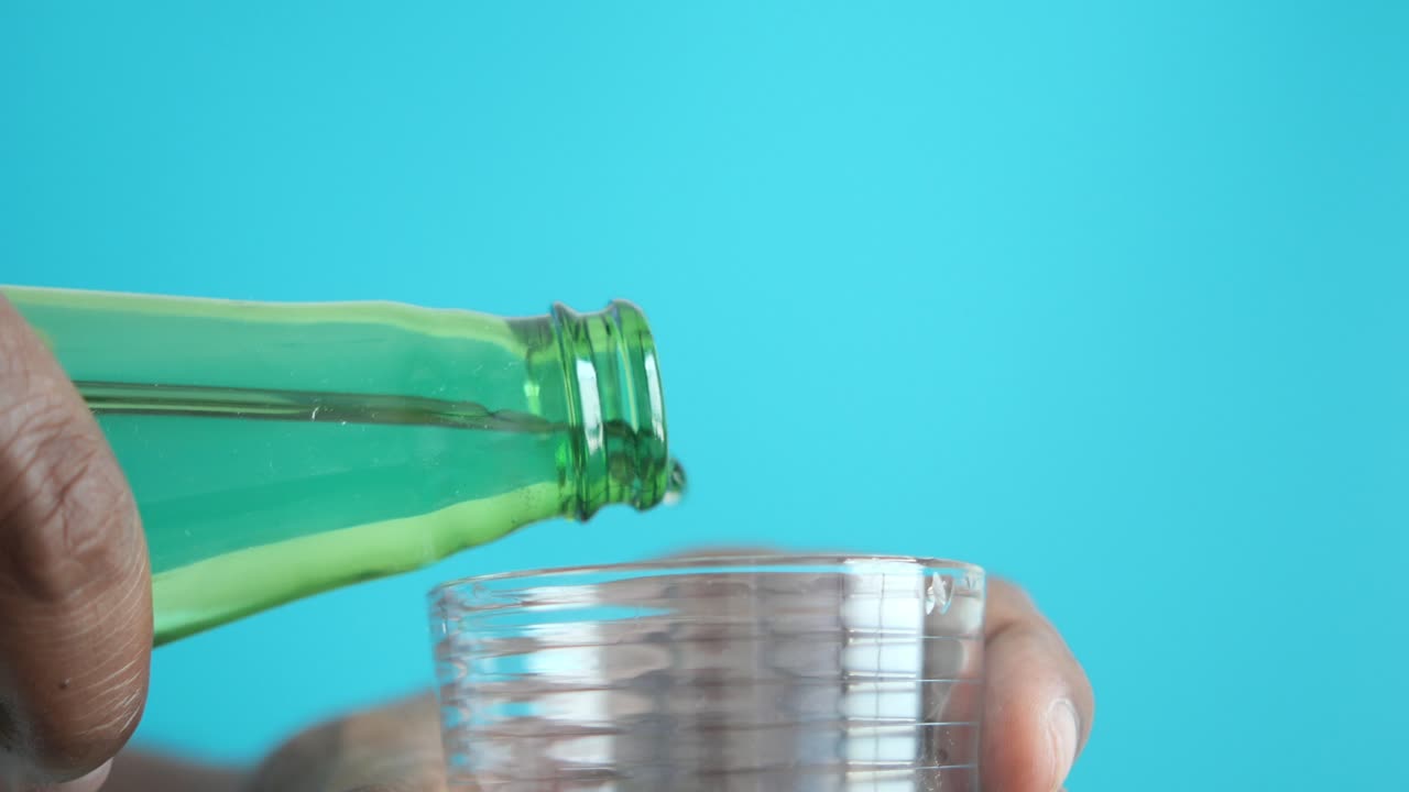 persona vertiendo agua de una botella en un vaso