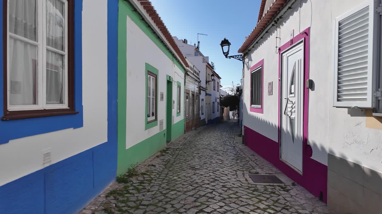 Colorful street in Ferragudo, Portugal, featuring bright painted houses and cobblestone path