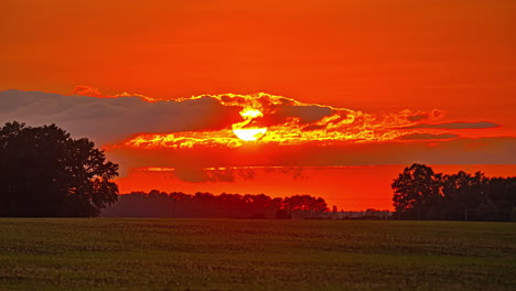 a breathtaking transformation of the sky as the sun sets, casting fiery orange and red hues while silhouetting the landscape below