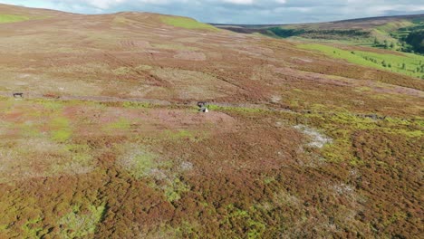 Aerial-pan-shot-of-a-tent-on-green-hill-during-sunny-day-in-Derbyshire,-England