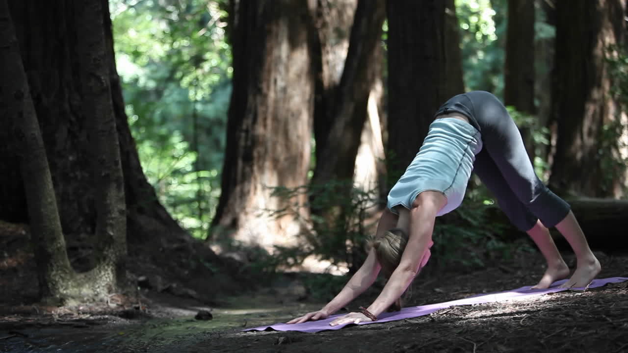 una joven caucásica practicando yoga en el bosque a lo largo de un río