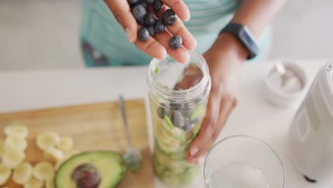 Midsection-of-african-american-woman-preparing-healthy-drink-in-kitchen