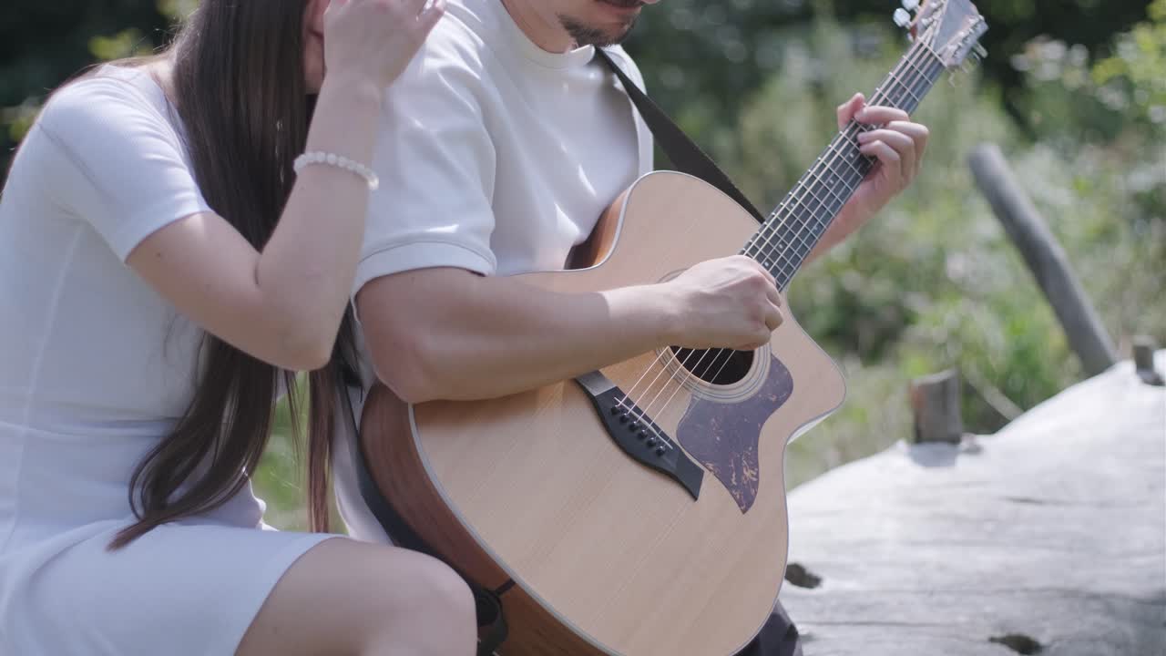 A couple playing guitar outdoors