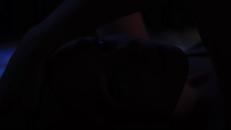 close up of a beautiful young woman lying in bed in a dark bedroom and looking at camera