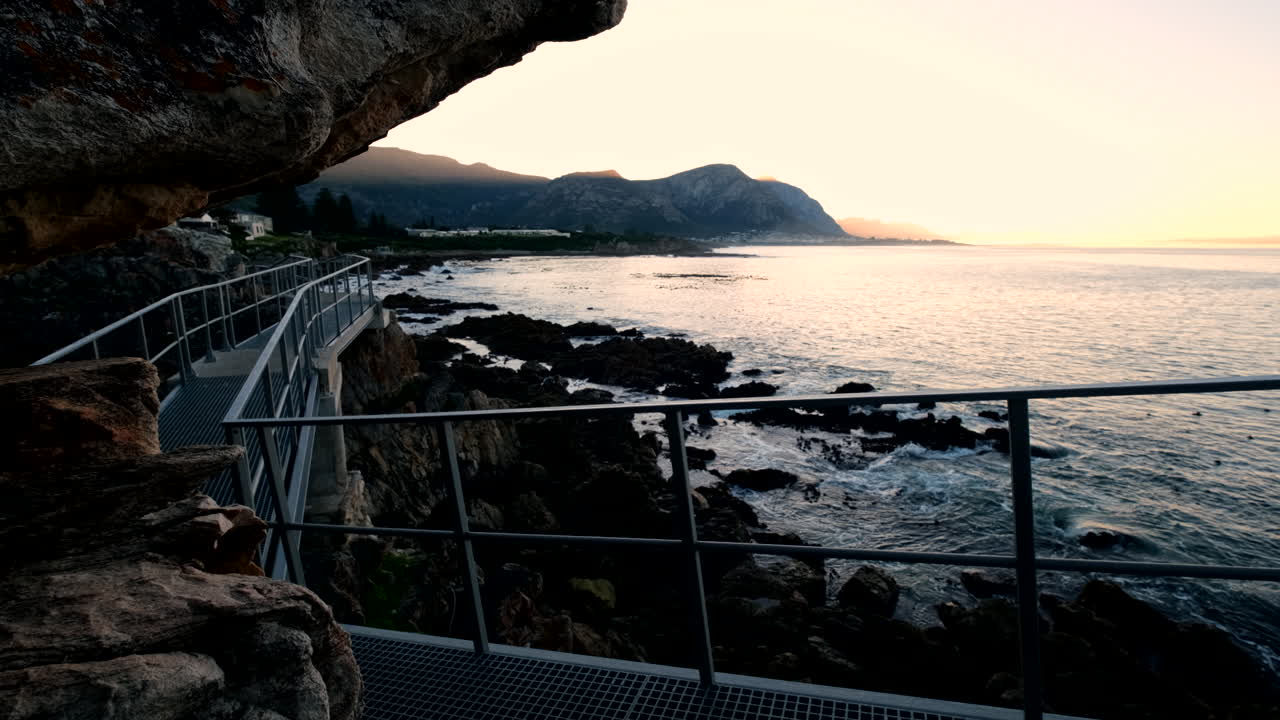 Yellow sunrise view from Hermanus Poole's Bay coastal path along rocky shore