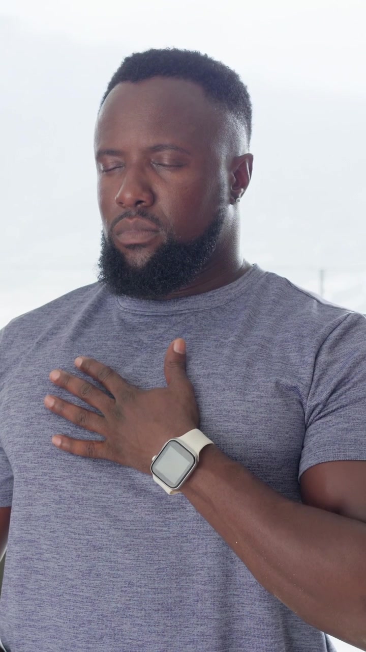 Vertical video: Placing hands man in gray tee breathing to relax at home camera moving right watch