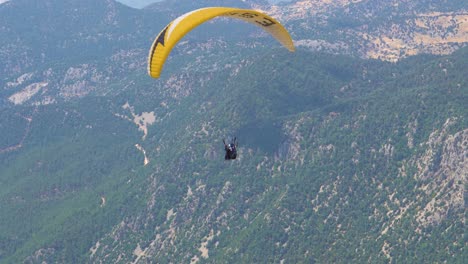 paragliders fly over mountain top in epic scenery