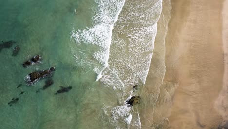 view from above of foamy waves at lusty glaze beach in newquay, cornwall