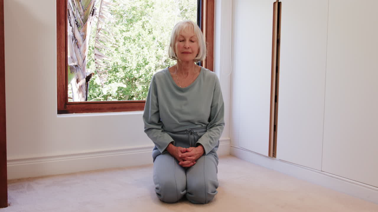 Senior woman meditating peacefully at home, eyes closed, embracing tranquility