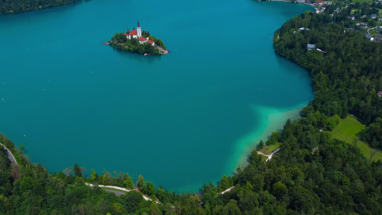 4K Birds Eye view of Lake Bled Island, beautiful turquoise blue water and green forest trees on lakeside shores - Lake Bled, Slovenia