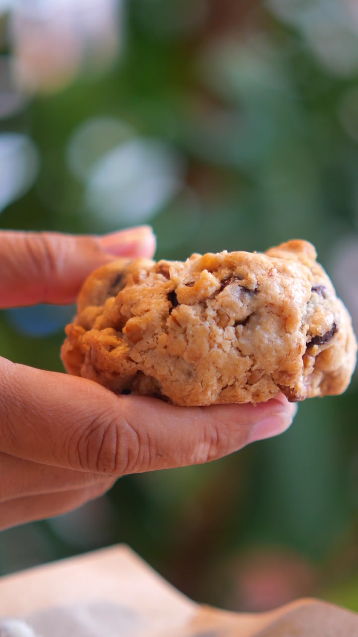 Hand Holding and Rotating a Delicious Chocolate Chip Cookie