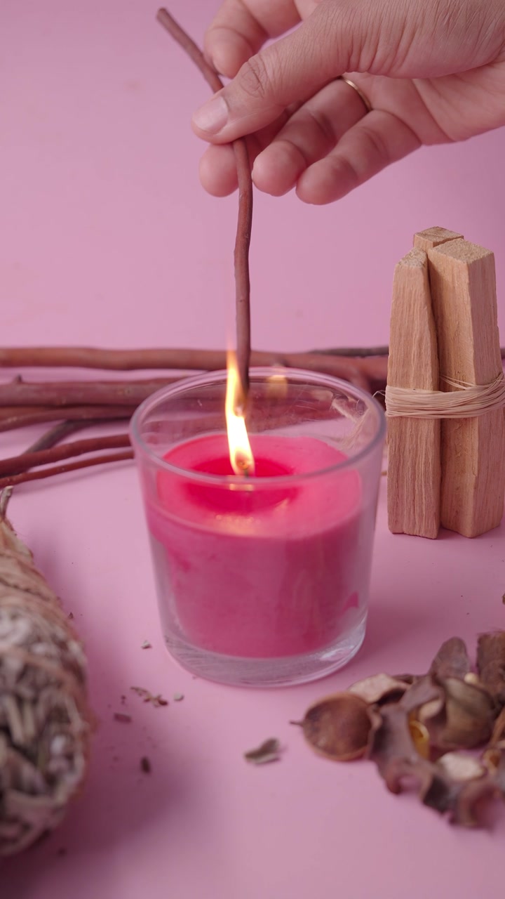 Hand Lighting a Palo Santo Stick with a Pink Candle