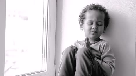 little boy praying to god with hands held together sitting on a window sill on white background stock video stock footage