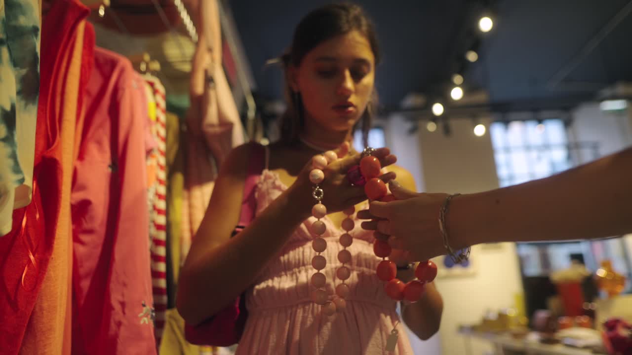 Woman holding an orange necklace in a boutique