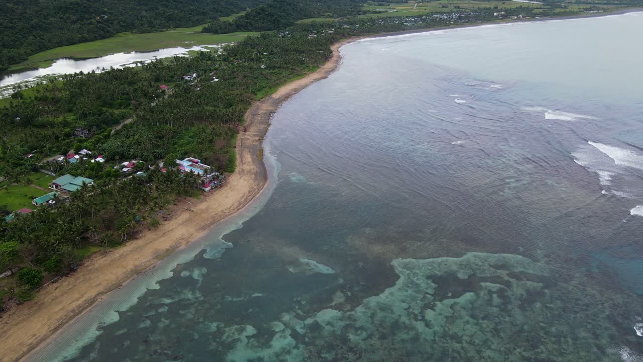 Scenic aerial flyover shot of tropical island coastline with fringing reef and transparent ocean waters at Catanduanes, Philippines