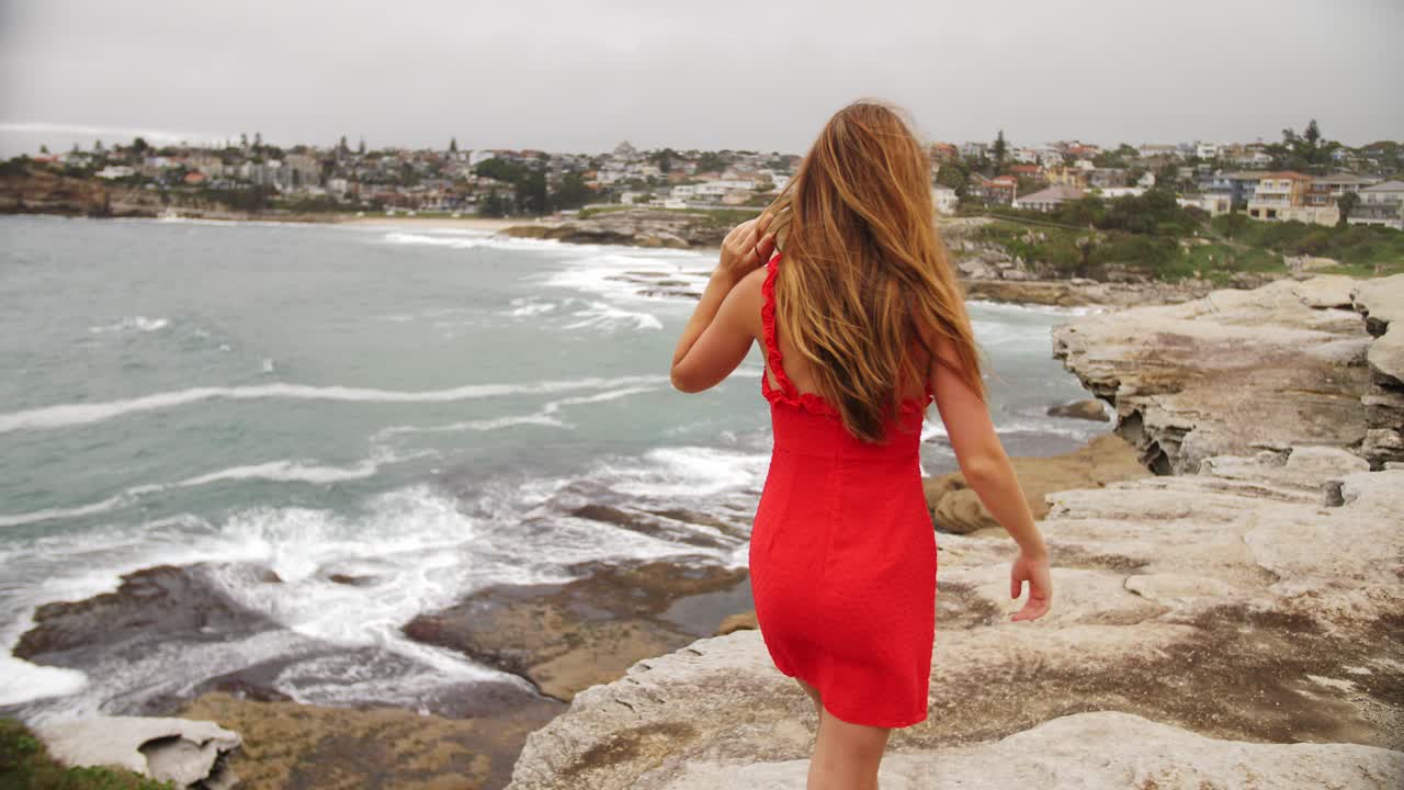 Lovely Lady In Sexy Red Dress Walking On The Rocky Shore - Eastern Suburbs Of Sydney In New South Wales, Australia - full slowmo shot