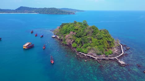 tourist boats surrounding a small tropical island in koh rong, cambodia, with crystal clear water and lush vegetation. best aerial view flight drone drone shot footage from above
