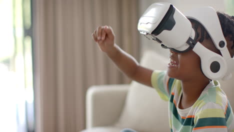 African-American-boy-enjoys-virtual-reality-at-home,-wearing-a-VR-headset-at-home