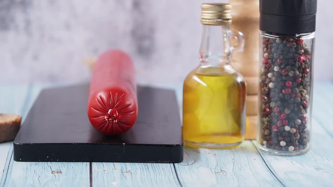 Salchicha en tabla de cortar con pan, aceite de oliva y pimienta