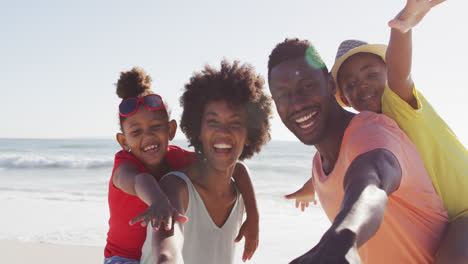 Portrait-of-smiling-african-american-family-embracing-on-sunny-beach