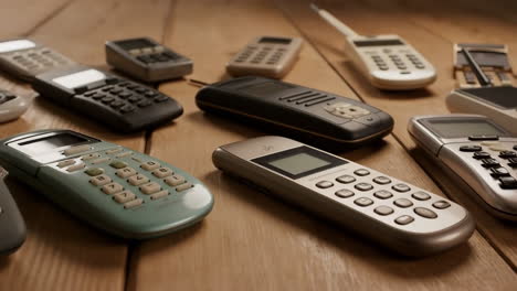 a collection of vintage mobile and cordless phones on a wooden table