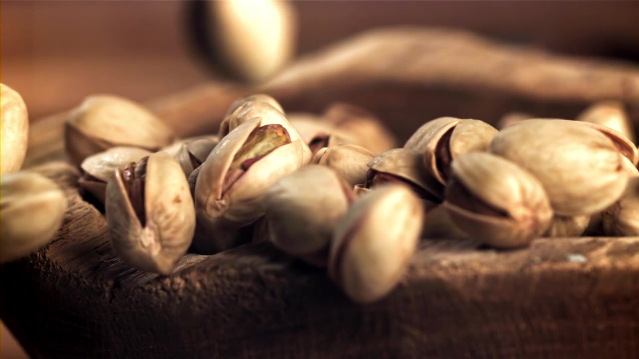 Pistacchi che cadono in una ciotola di legno rustica al rallentatore.