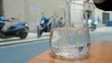 pouring water into a glass on a sunny day in a city