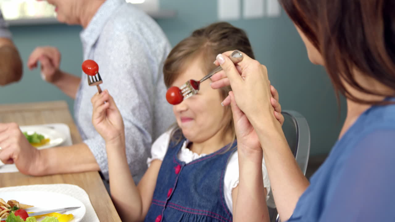 madre y hija felices sentadas a la mesa