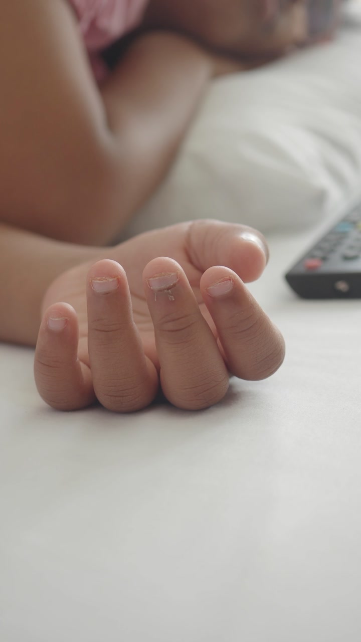 Close-up of Child's Hand Resting on Bed While Sleeping