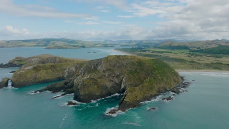 scenic aerial view of wild and rugged coastal landscape with large rocky outcrop of land in remote catlins, south island of new zealand aotearoa