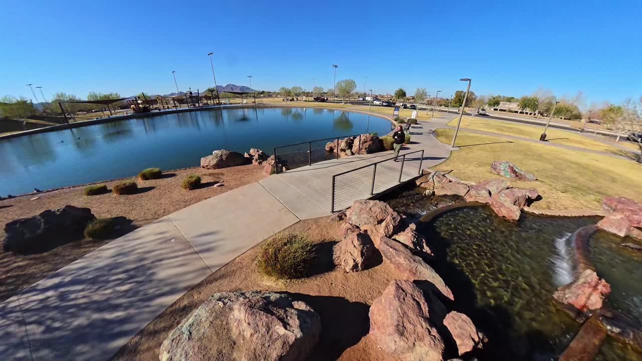 Static Red haired male walking by fountains Mansel Crater Park in Queen Creek Arizona.
