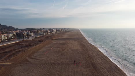 Castelldefels-Beach-near-Barcelona-with-people-and-cityscape,-clear-sky,-aerial-view